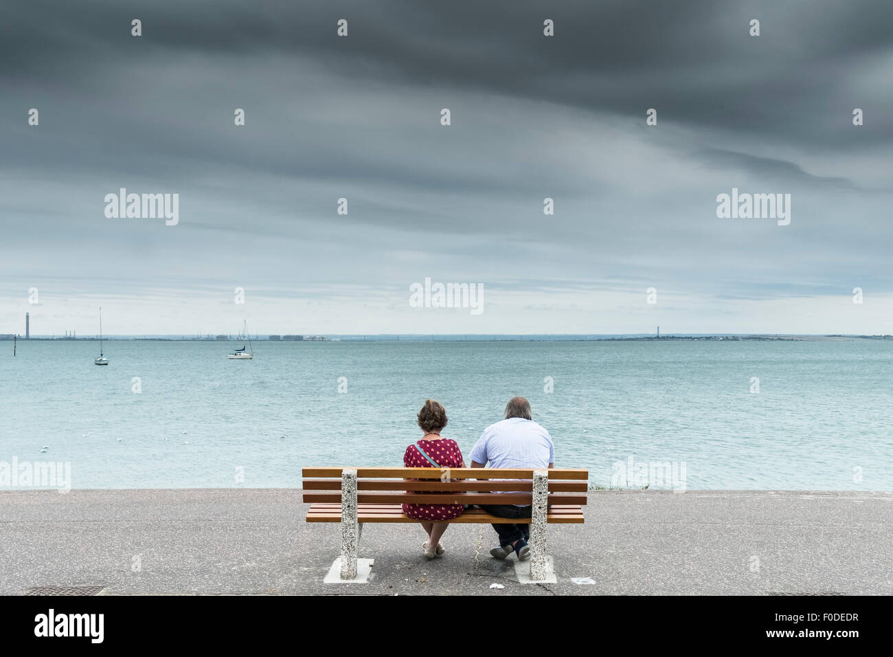 Una coppia che si rilassa su una panchina che guarda all'estuario del Tamigi a Southend in Essex nel Regno Unito. Foto Stock