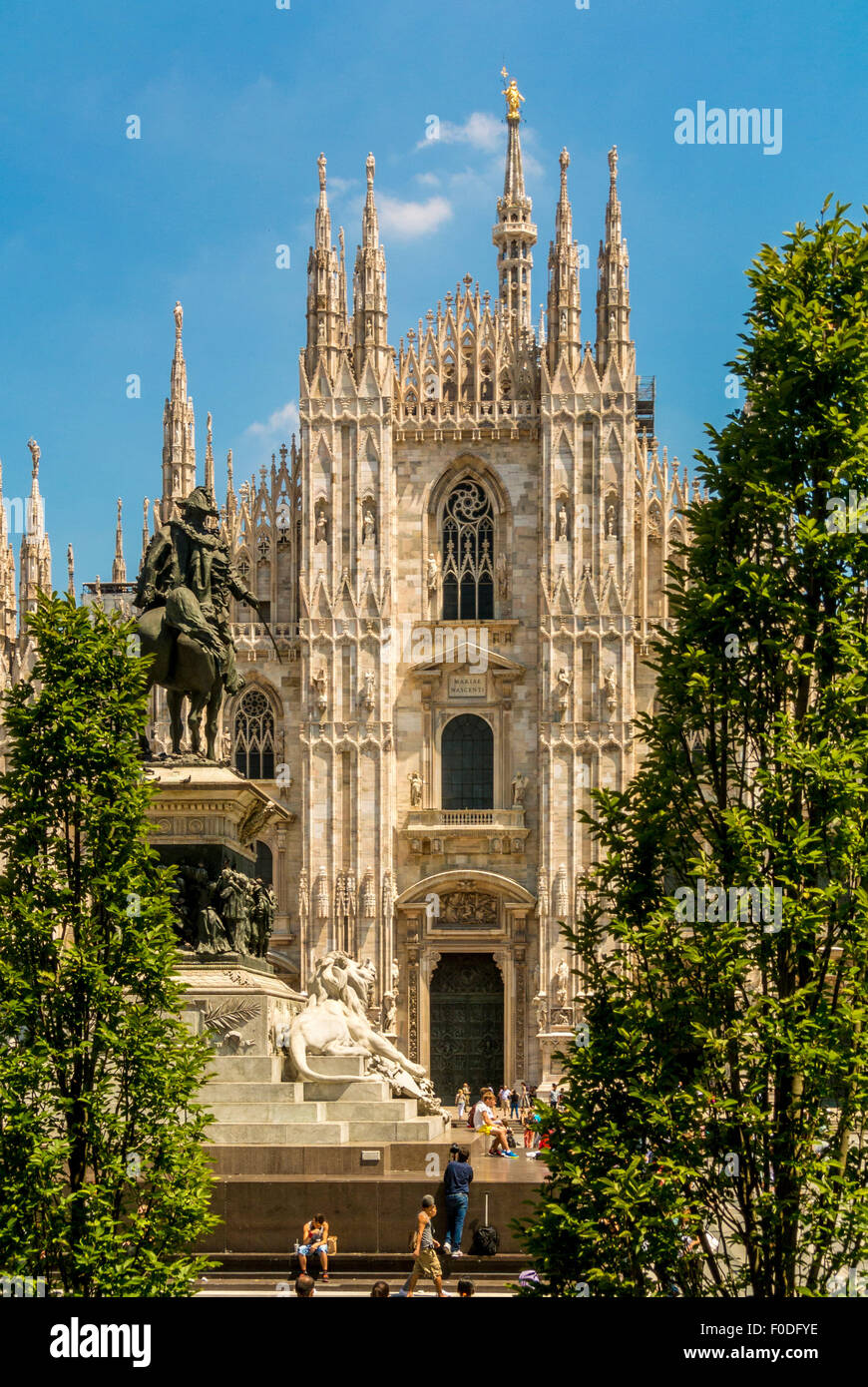 Duomo di Milano con la statua del re Vittorio e gli alberi in primo piano, visti contro un cielo blu a Milano. Italia. Foto Stock
