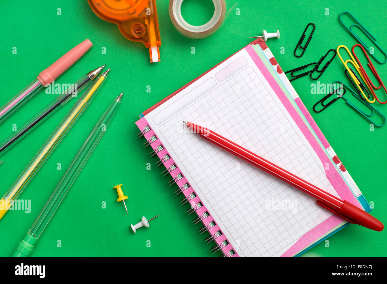 Scuola materiali come pastelli, notebook, clip, cucitrice, prencils su sfondo verde Foto Stock