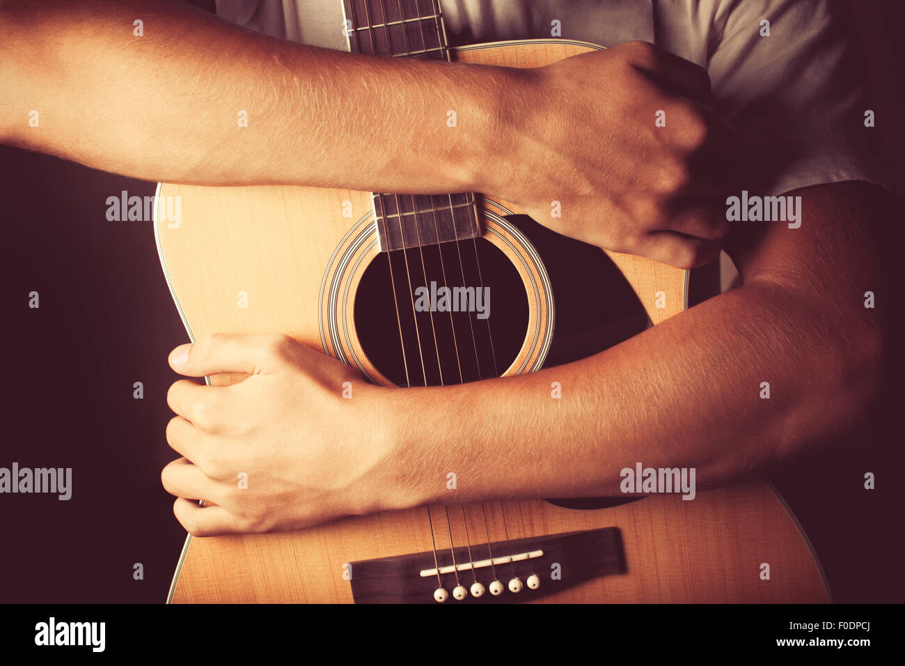 Mani tenendo una chitarra acustica Foto Stock