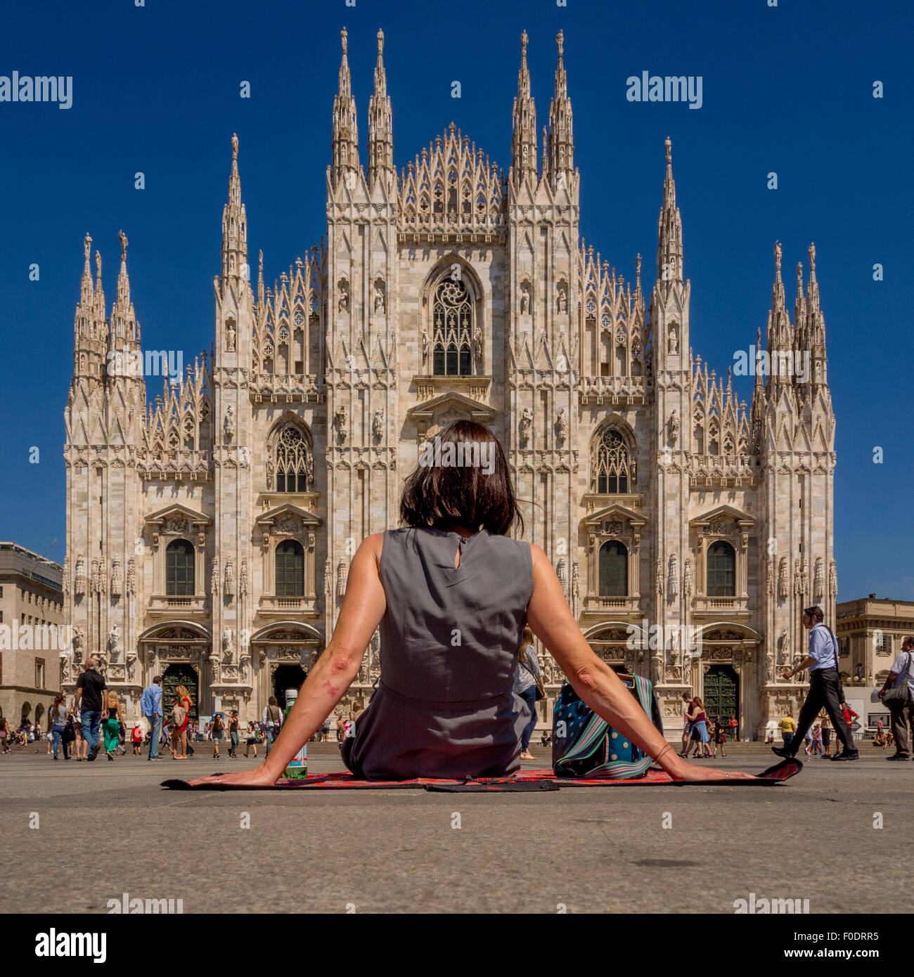 Turista femminile seduto su una coperta picnic, sul terreno al di fuori del Duomo di Milano. Italia Foto Stock