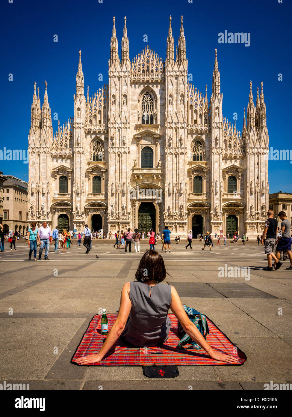 Turista femminile seduto su una coperta picnic, sul terreno al di fuori del Duomo di Milano. Italia Foto Stock