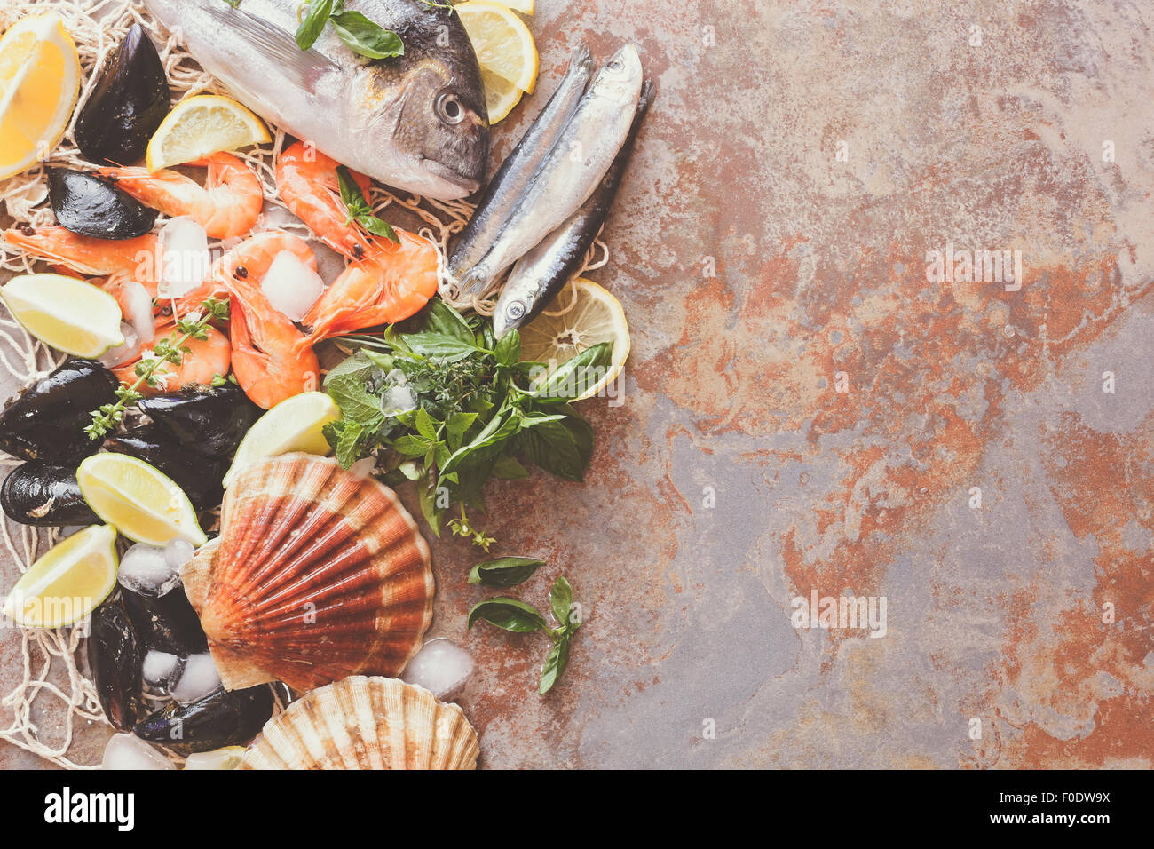 Assortimento di frutti di mare. Colpo di overhead di materie capesante, pesce, gamberi e cozze con limone e spezie su ghiaccio tritato Foto Stock