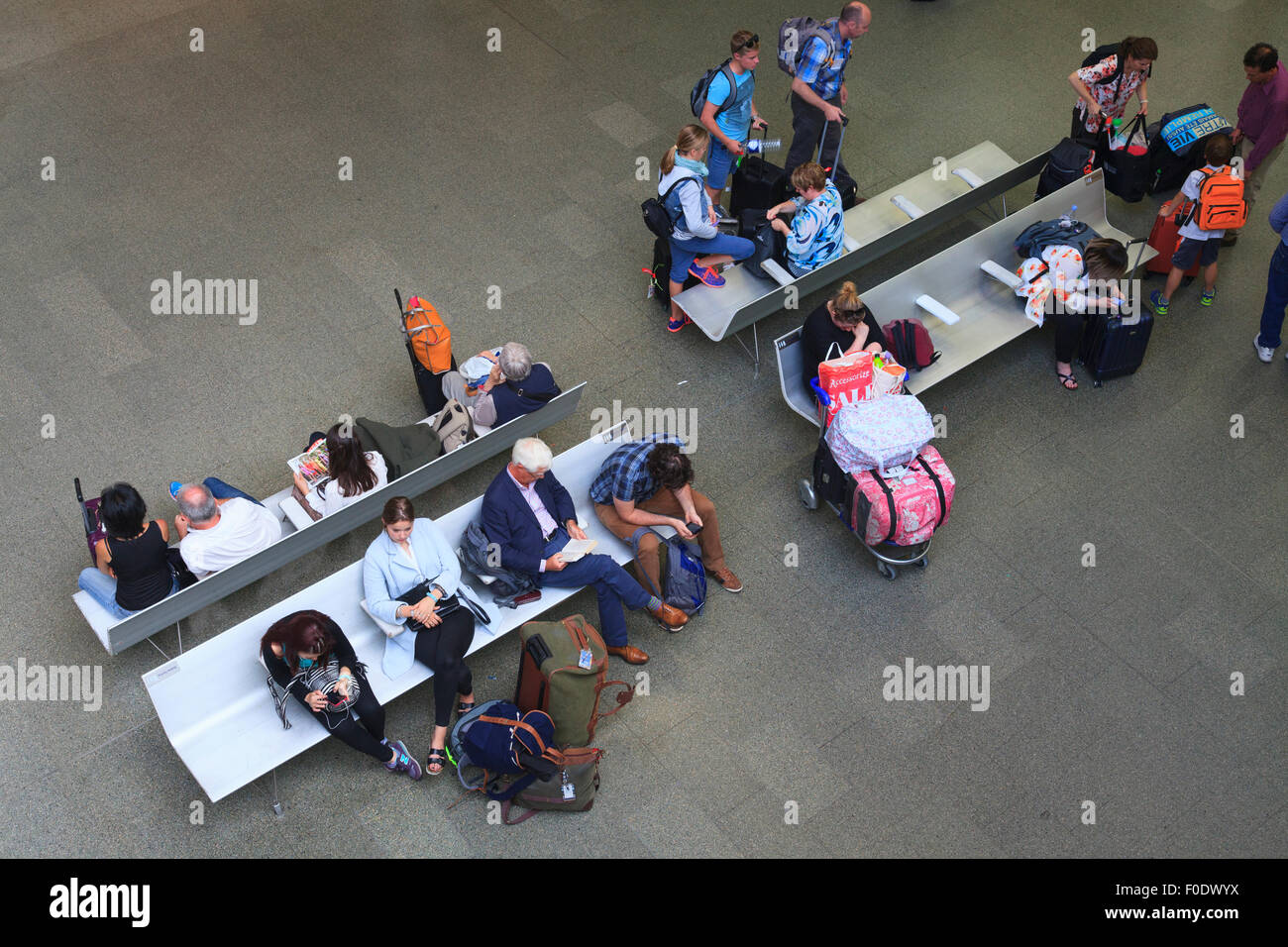 Guardando verso il basso sui passeggeri e viaggiatori seduti sui banchi in attesa a St Pancras Foto Stock