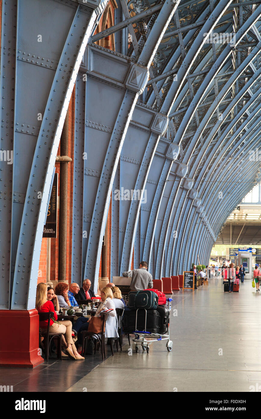 I viaggiatori seduti sotto l opera di carpenteria metallica di St Pancras Stazione ferroviaria London Foto Stock