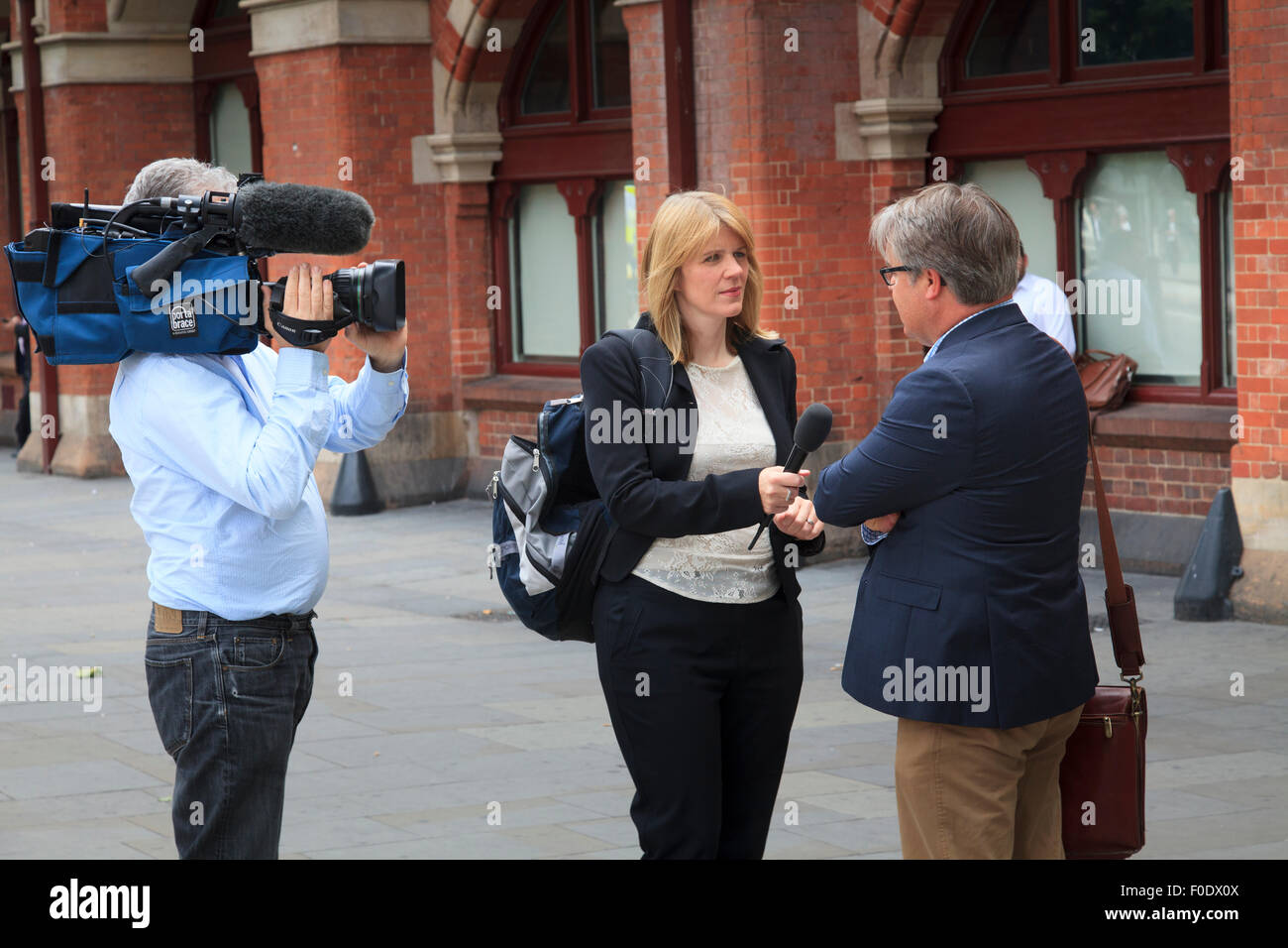 Reporter femmina e la telecamera uomo viaggiatore intervista a St Pancras Foto Stock