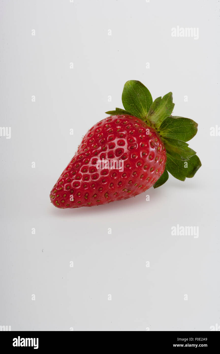 Single fragole mature su sfondo grigio Foto Stock