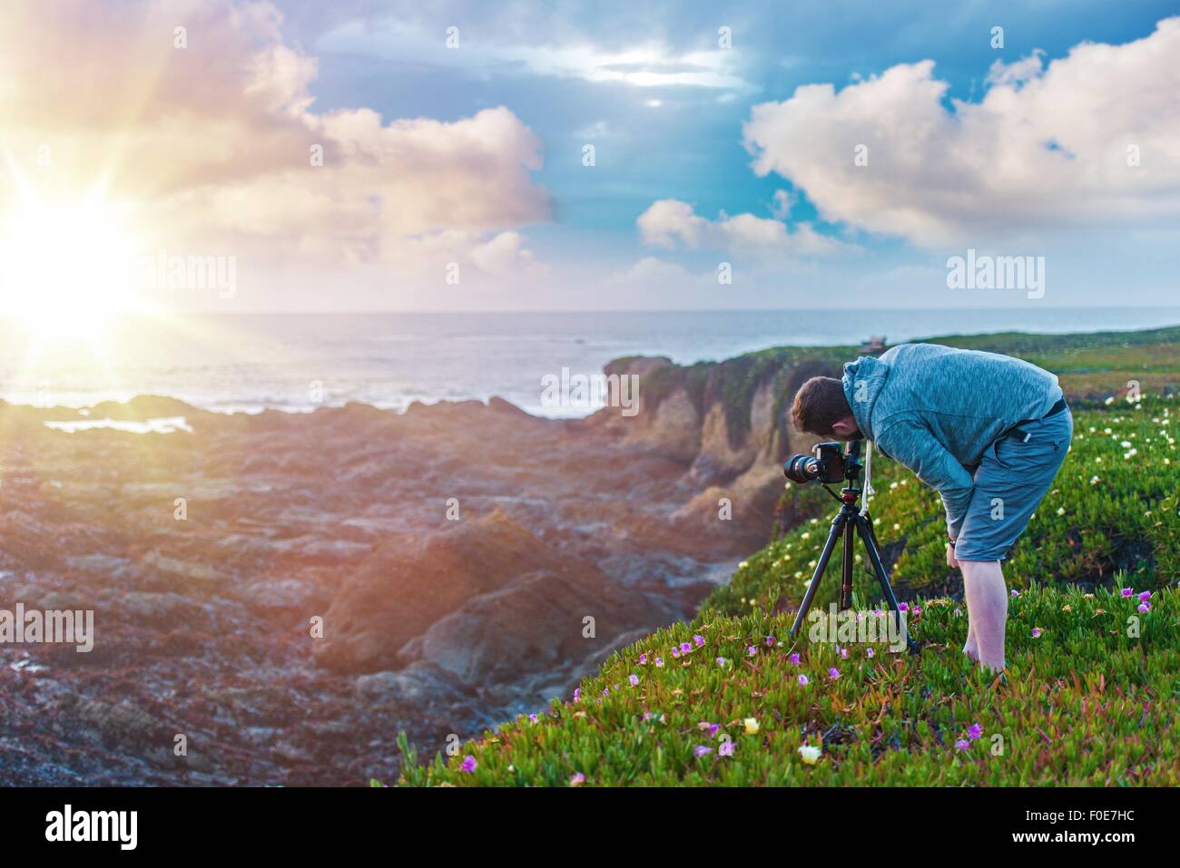 La fotografia naturalistica. Fotografo sull'oceano Cliff prendendo immagini di tramonti. Foto Stock