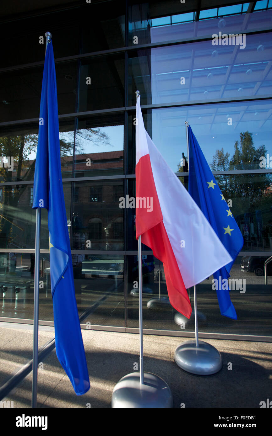 Europa e bandiere polacche flottante in una conferenza europea in Polonia con windows in background Foto Stock