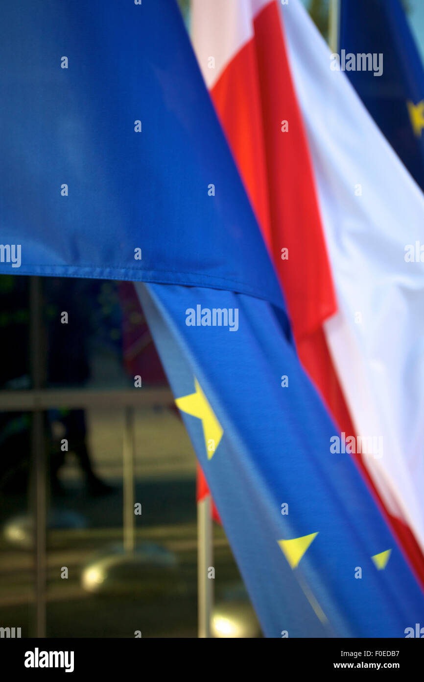 Europa e bandiere polacche flottante in una conferenza europea in Polonia con windows in background Foto Stock