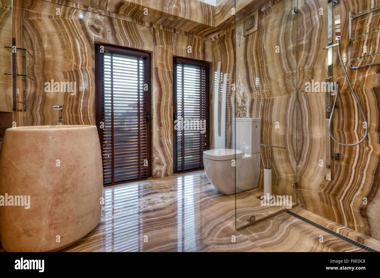 Interno di bagno moderno in marmo. Bagno lussuoso con pareti in marmo, rubinetteria moderna e doccia separata in vetro Foto Stock