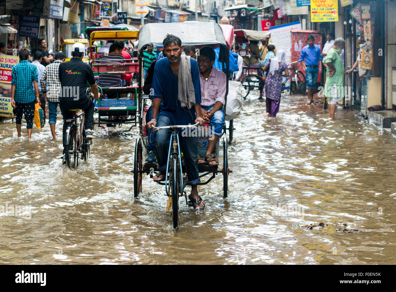 Persone e risciò ciclo si stanno spostando attraverso le strade inondate del sobborgo Paharganj dopo un pesanti piogge monsoniche Foto Stock
