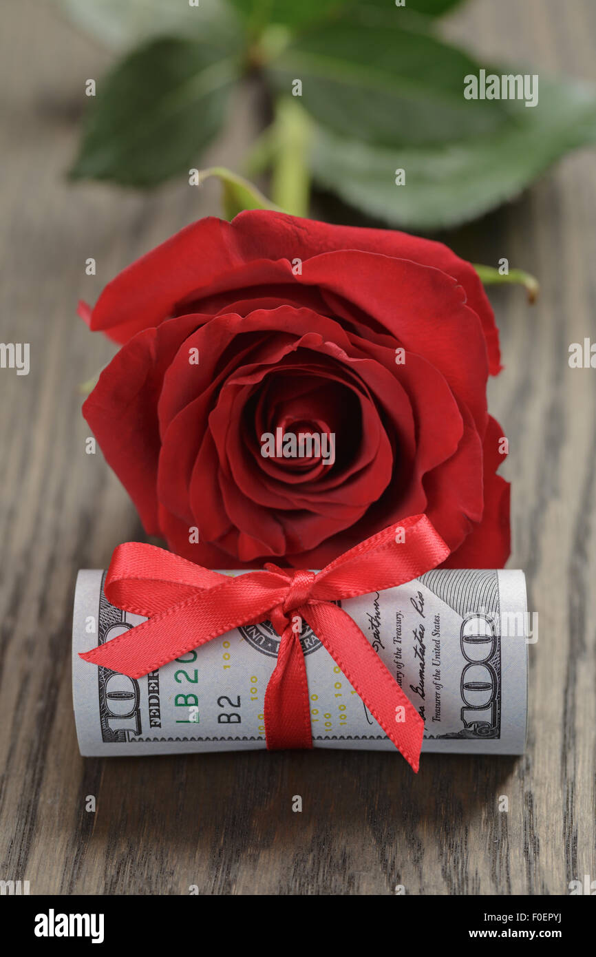 Single red rose e mazzo di fatture del dollaro Foto Stock