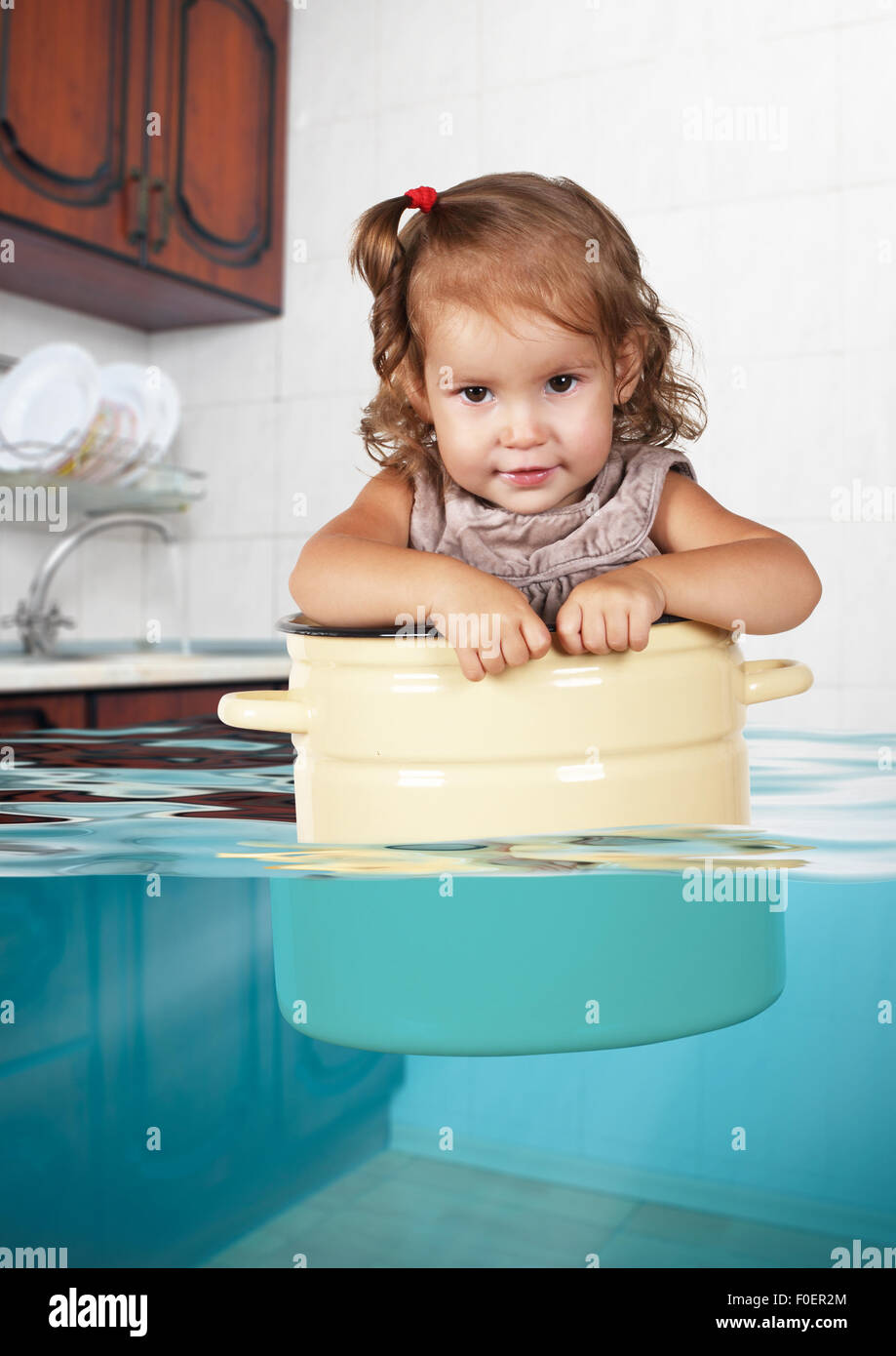 Funny ragazzino nuotare in padella in cucina allagata, turbolenti concetto creativo Foto Stock