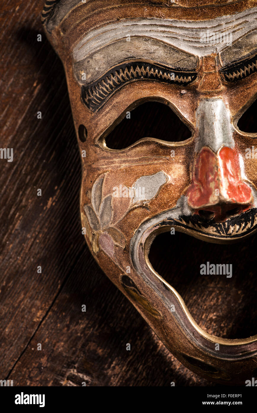 Maschera di commedia giacente su sfondo di legno. Ancora vita che mostra la felicità e la espressione positiva attraverso un oggetto. Foto Stock