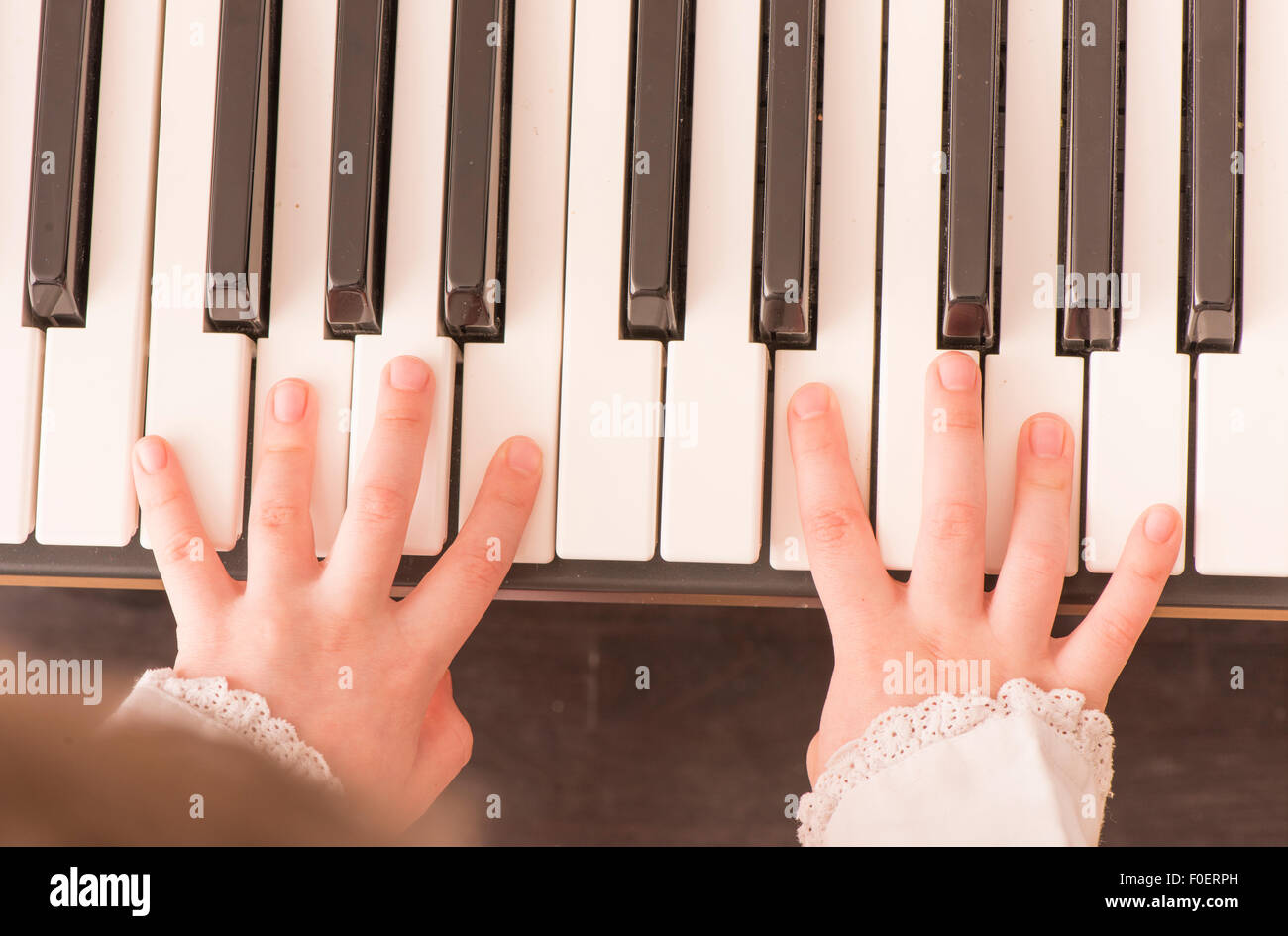 Stretta di mano del bambino suonare il pianoforte. Vista superiore della bambina pratica per la sua musica. Foto Stock