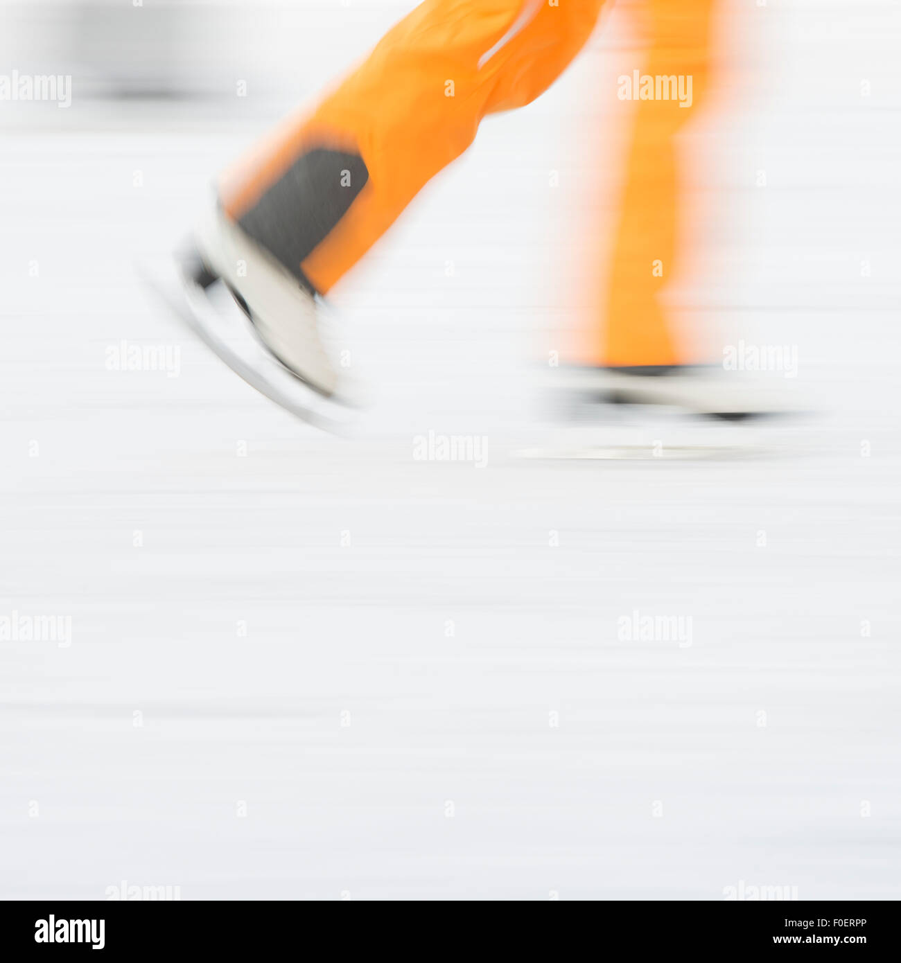 Vista laterale di uomo adulto pattinaggio sul ghiaccio nel parco. Immagine sfocata che mostra la velocità e movimento. Foto Stock