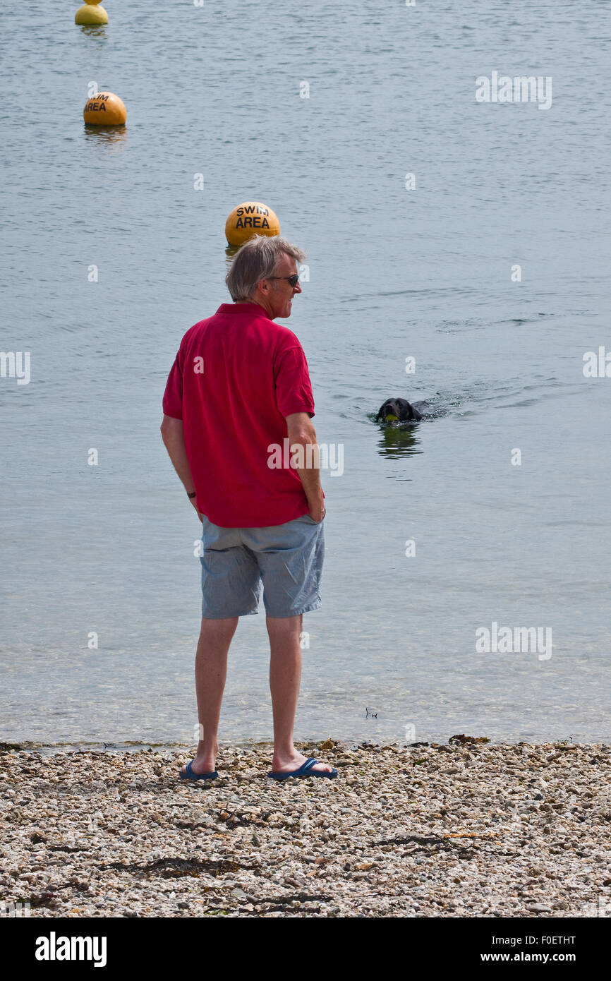 Piaceri semplici - un uomo e il suo cane godendo il mare su una spiaggia della Cornovaglia Foto Stock