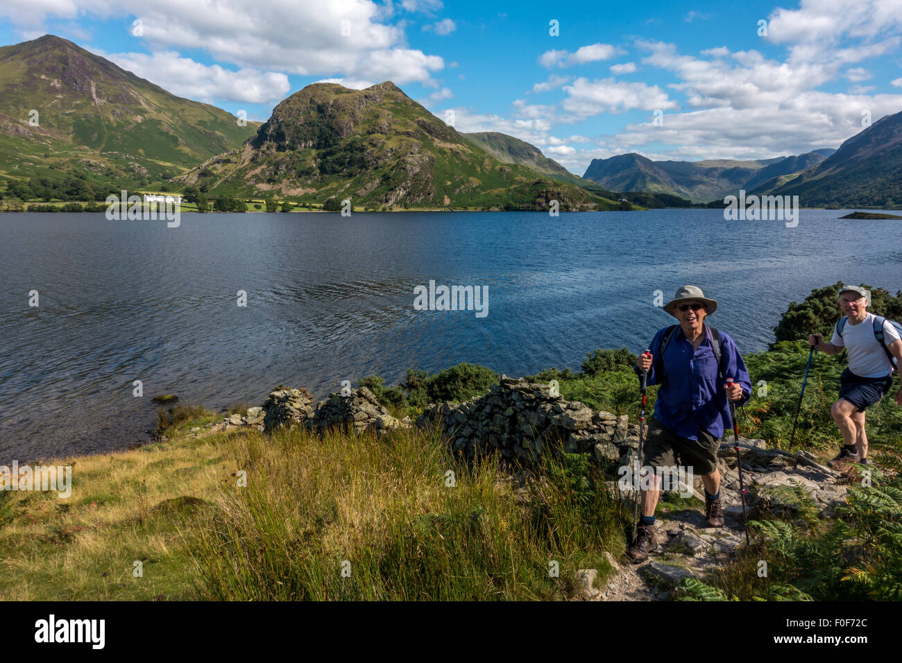 Seniors lifestyle: due persone di ritorno da una passeggiata lungo la bella riva occidentale del Crummock acqua, Lake District inglese, REGNO UNITO Foto Stock