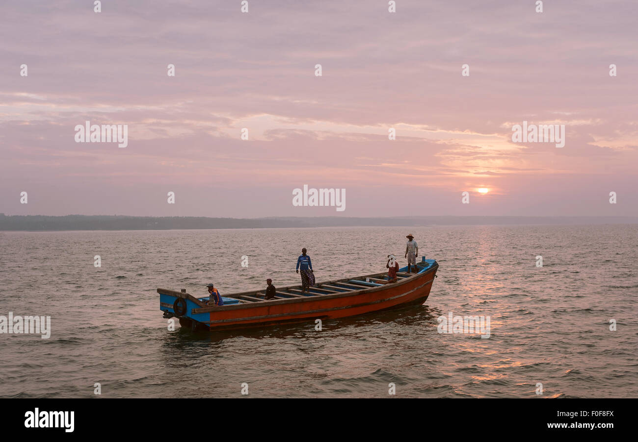 Una squadra di pescatori escono in una piccola barca di legno per una giornata di pesca in mare profondo fuori la Costa di Malabar. Foto Stock