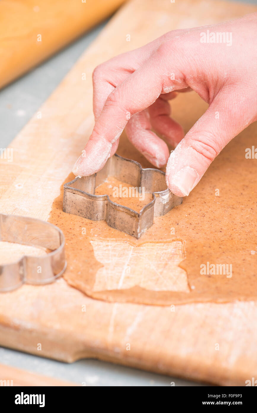 La mano della donna la cottura del pane di zenzero cookies come preparazione di natale. Foto Stock