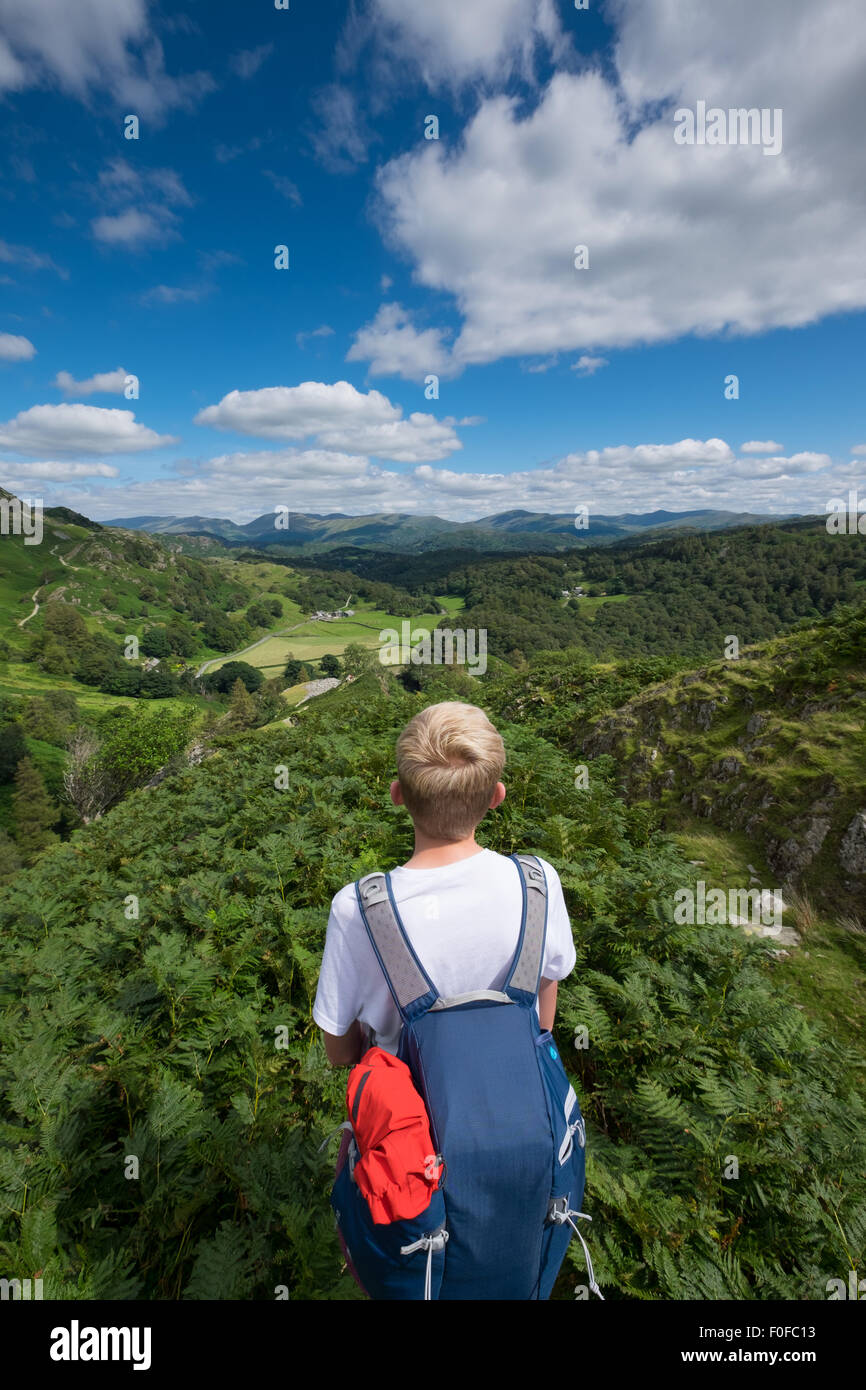 Un ragazzo adolescente si affaccia in tutta l'orizzonte pronto per un'avventura all'aperto nel distretto del lago, Cumbria, Regno Unito Foto Stock