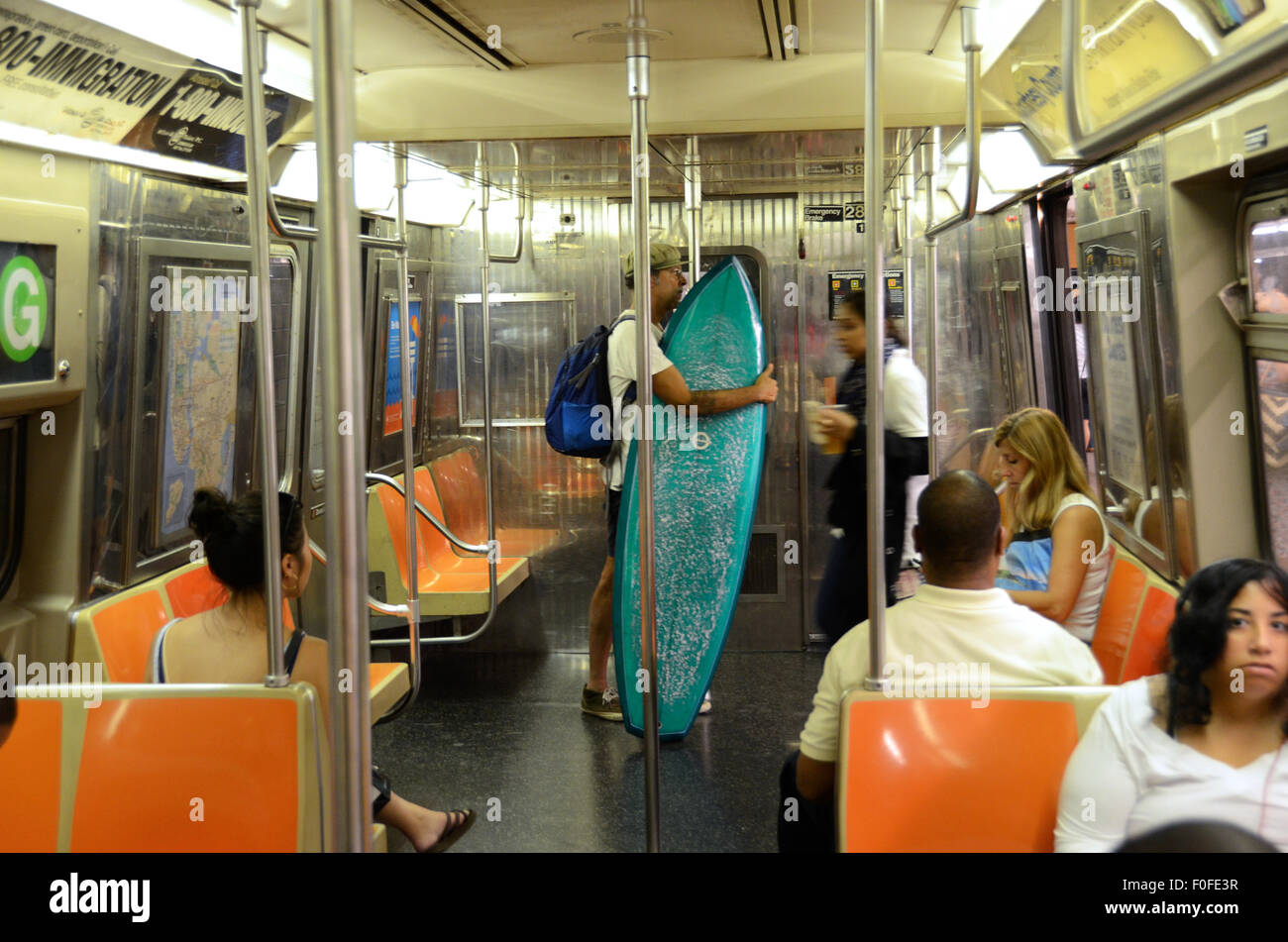 L'uomo con la tavola da surf sul new york subway scheda blu G treno Foto Stock