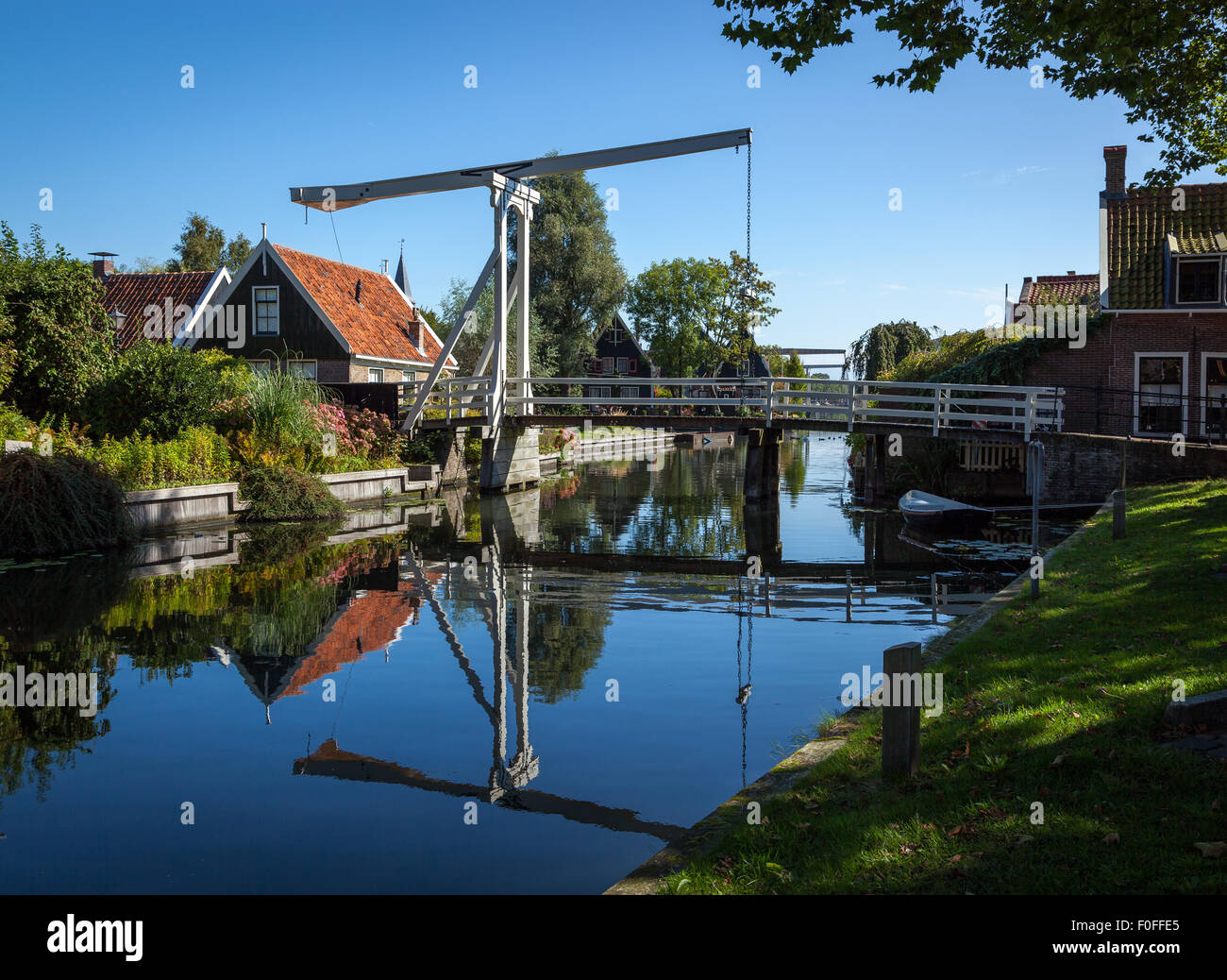 Tradizionale impostazione rurale di un piccolo villaggio in Olanda, Paesi Bassi. Piede di sospensione Bridge crossing over teh fiume. Foto Stock