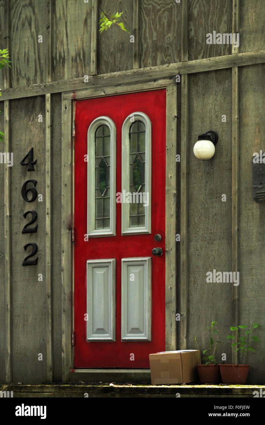 Pacchetto consegnato accanto a un rosso, porta rustica in Okemos, Michigan, Stati Uniti d'America. Foto Stock