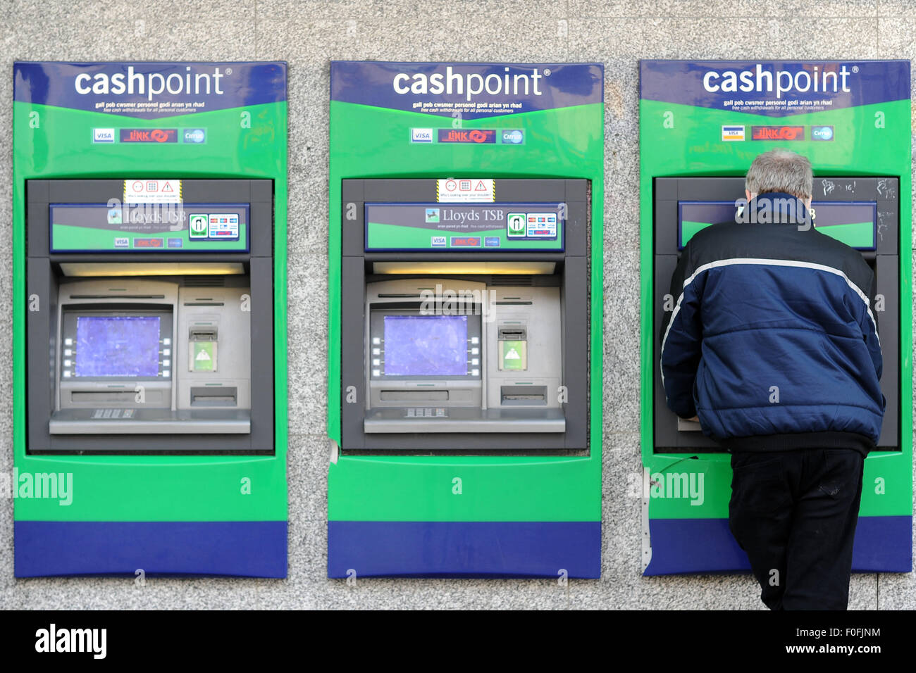 Un uomo utilizza un Lloyds TSB Bank bancomat (ATM) sulla strada alta. Foto Stock