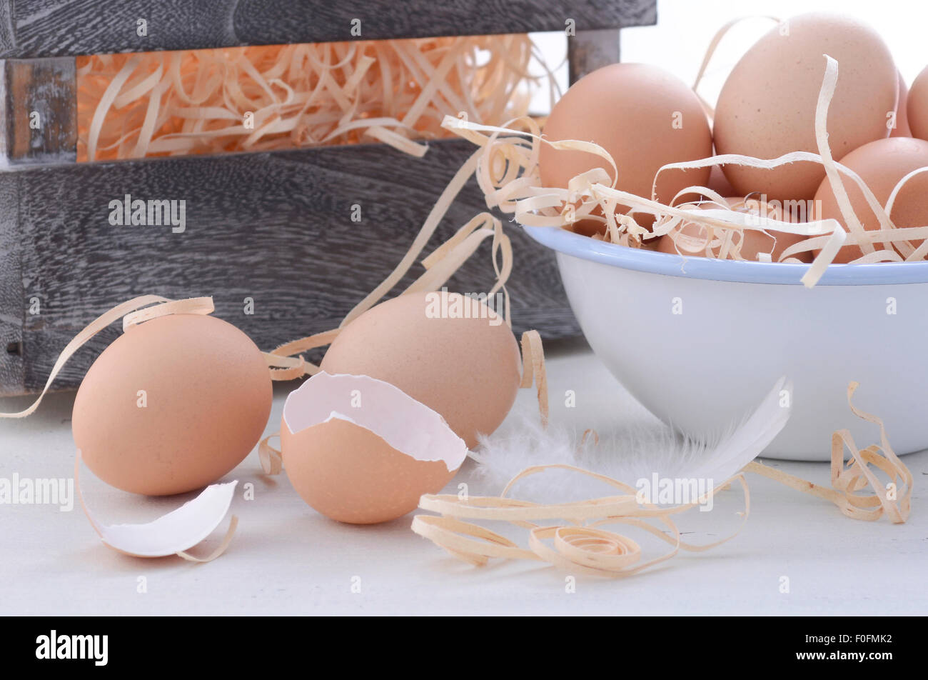 Fattoria fresco uova nella ciotola con il deposito di legno sulla cassa vintage white background in legno, primo piano. Foto Stock