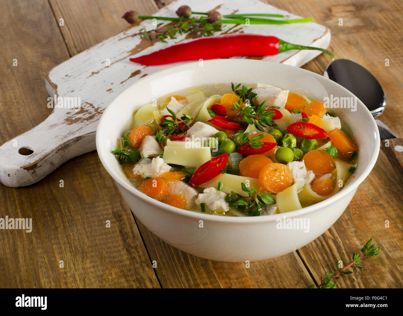 Ciotola di zuppa di pollo con verdure e tagliatelle sul tavolo di legno Foto Stock