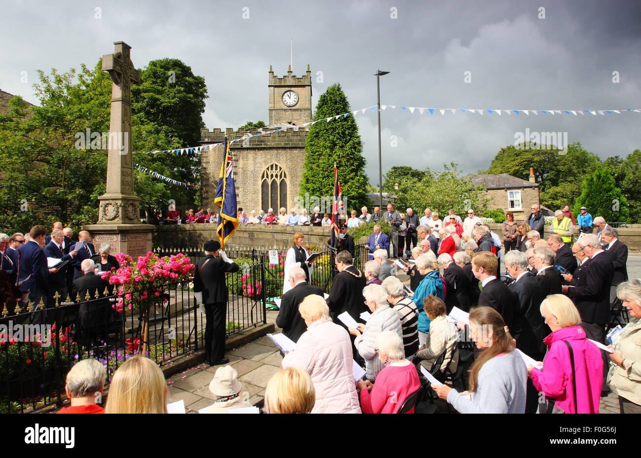 Hayfield, High Peak, Derbyshire, Regno Unito. Il 15 agosto 2015. L'Hayfield ramo della Royal British Legion segna la vittoria sul Giappone giornata con un servizio speciale di ringraziamento al Hayfield Memoriale di guerra in questo centro di questo piuttosto elevati picchi di borgo ai margini del Parco Nazionale del Peak District. Il Led dal ramo cappellano il reverendo Ilario Edgerton, il servizio contrassegnato in occasione del settantesimo anniversario della vittoria sulle forze giapponesi. Credito: Matthew Taylor/Alamy Live News Foto Stock