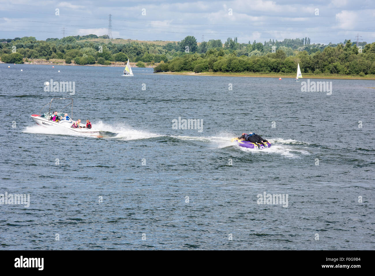 Due uomini con un giro su di un grande anello gonfiabile dietro un motoscafo sul lago a Chasewater Country Park lichfield, Regno Unito Foto Stock