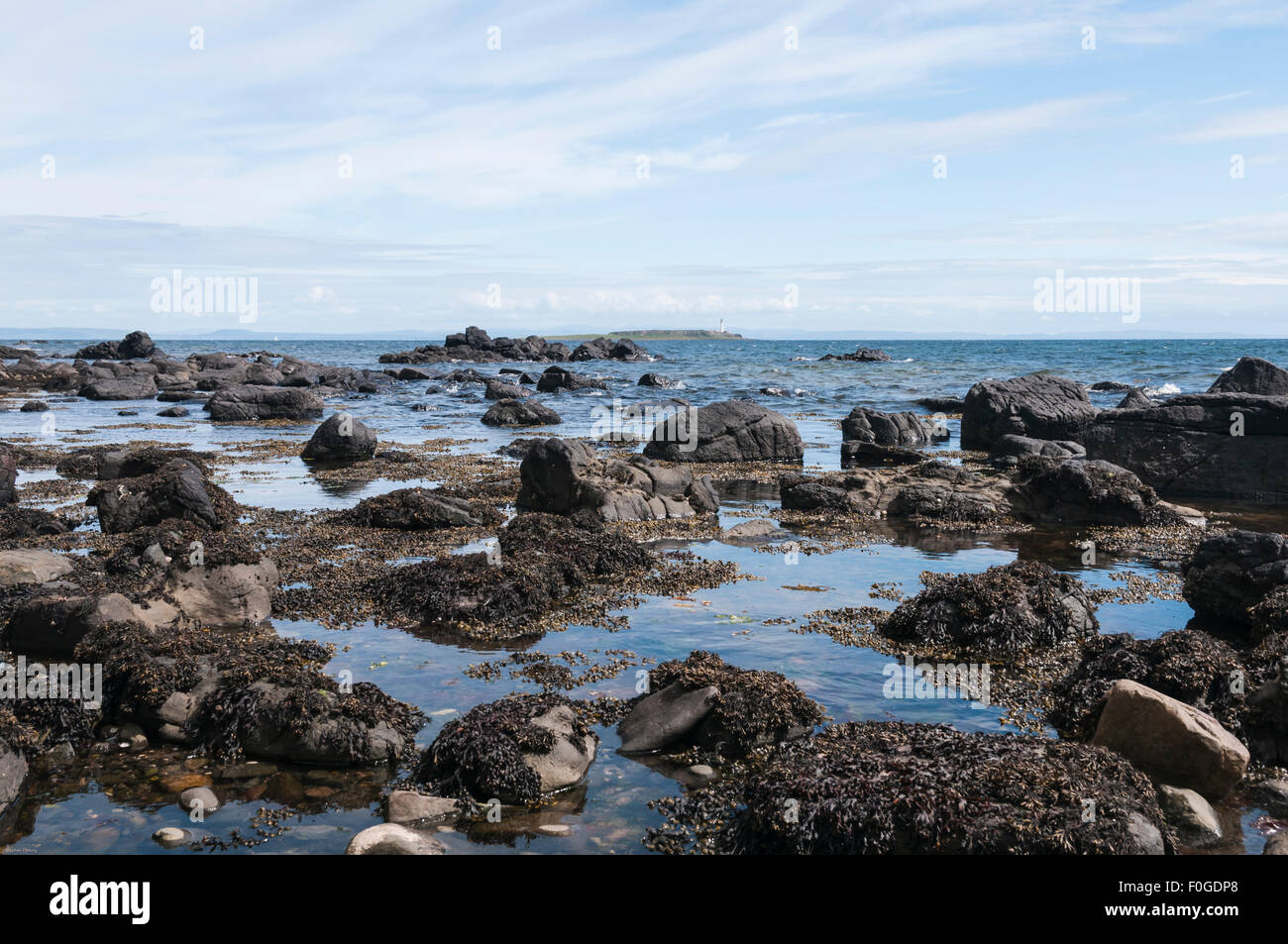 Il litorale a Kildonan, Isle of Arran, guardando in lontananza al faro su Pladda, Scozia Foto Stock