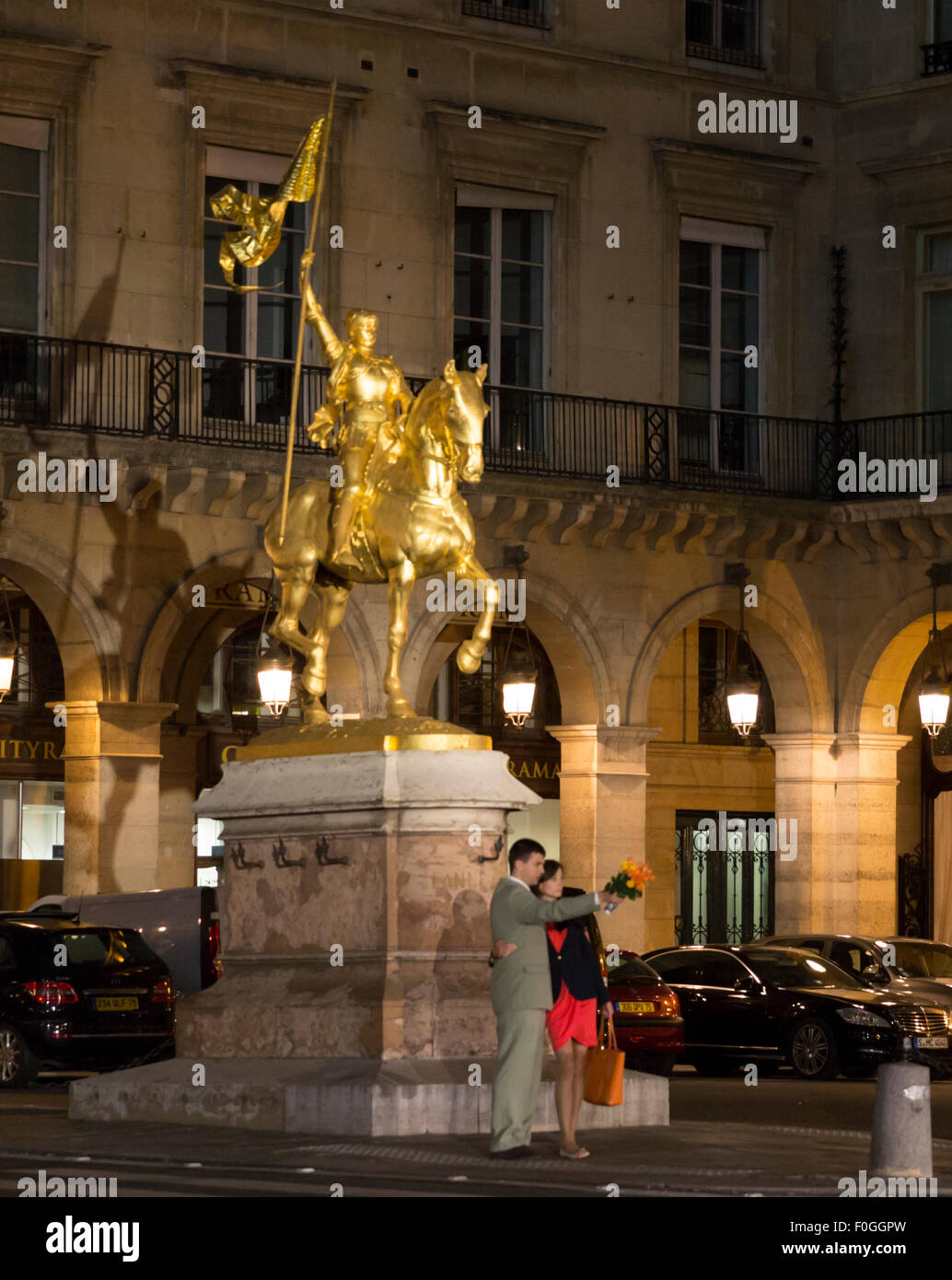 Vista notturna di giovane in piedi di fronte degli illuminati Jeanne d'Arc statua nella Place des Pyramides, Parigi Francia Foto Stock
