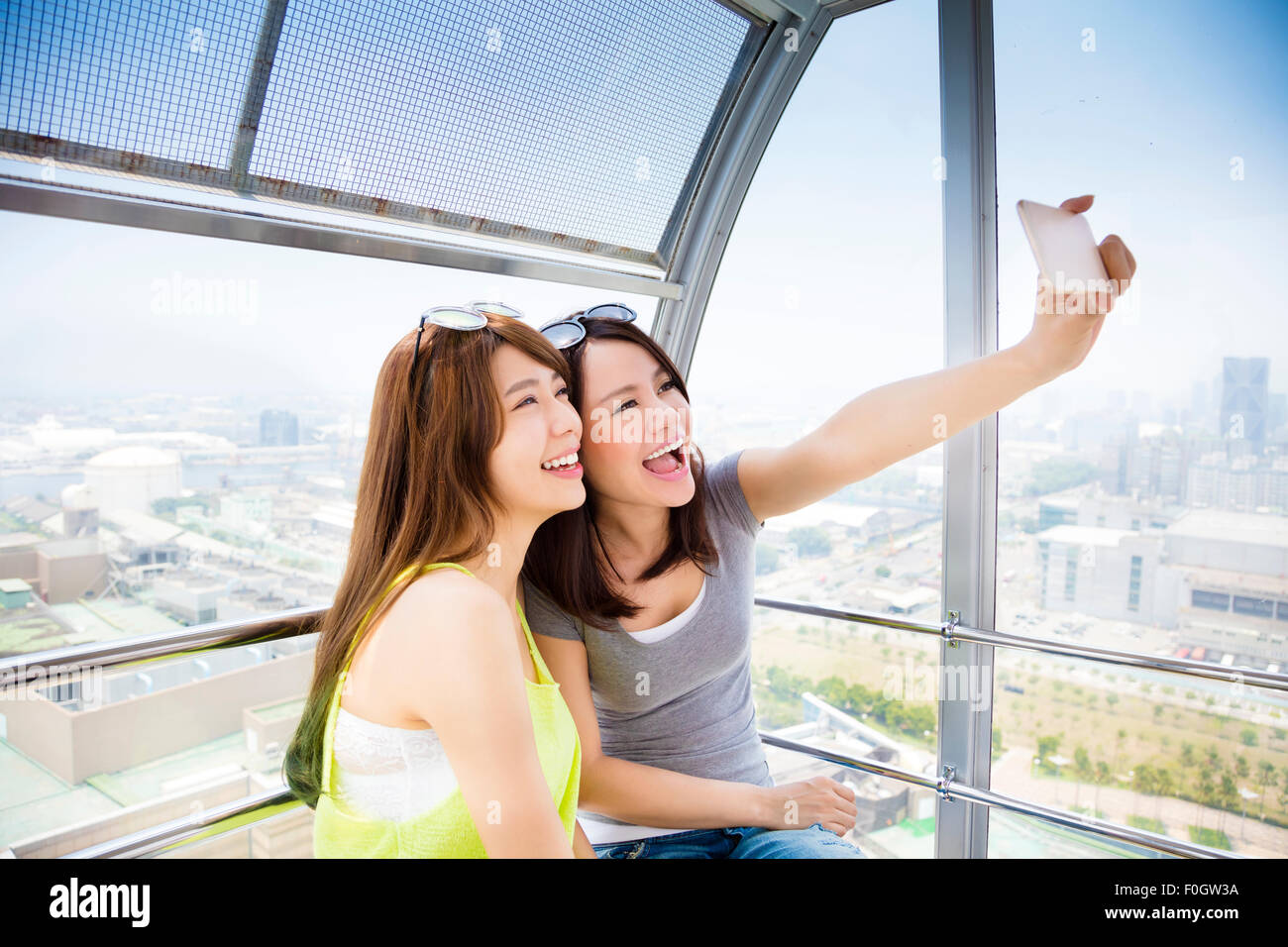 Felici donne fidanzate prendendo un selfie nella ruota panoramica Ferris Foto Stock