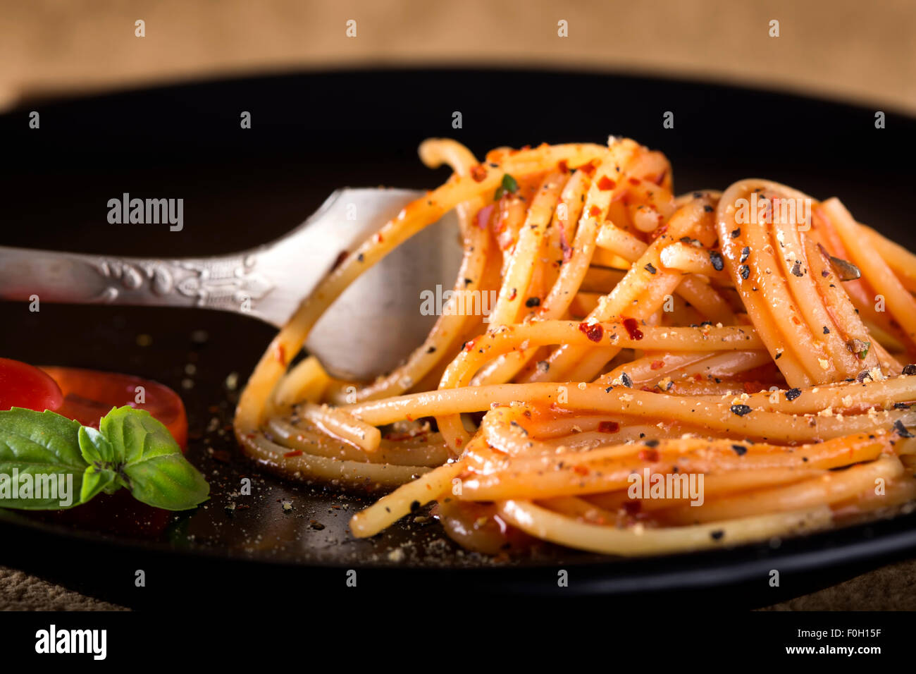 Spaghetti italiana della forcella al buio su un piatto con basilico e salsa di pomodoro Foto Stock