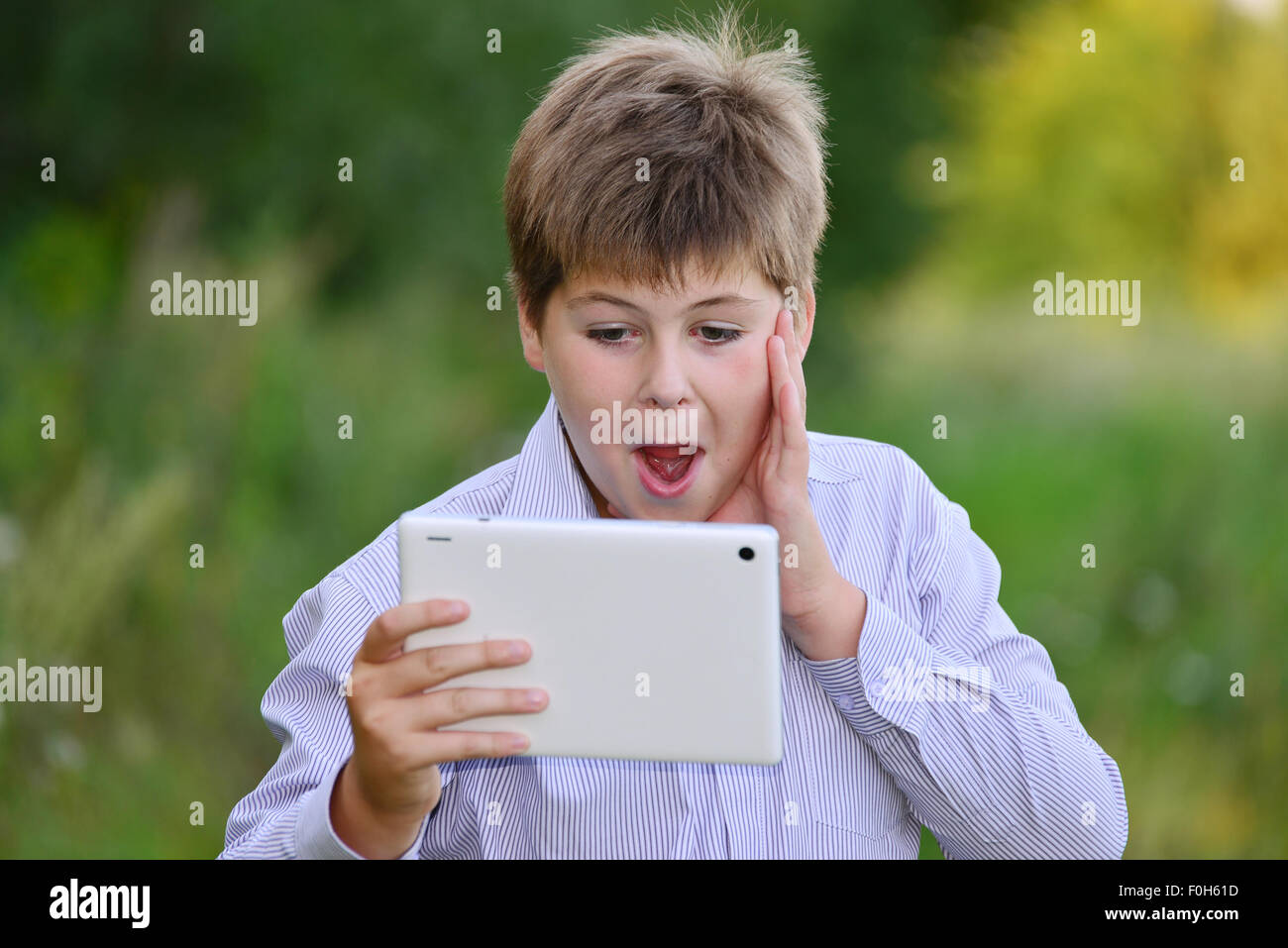 Teen boy con computer tablet in natura Foto Stock
