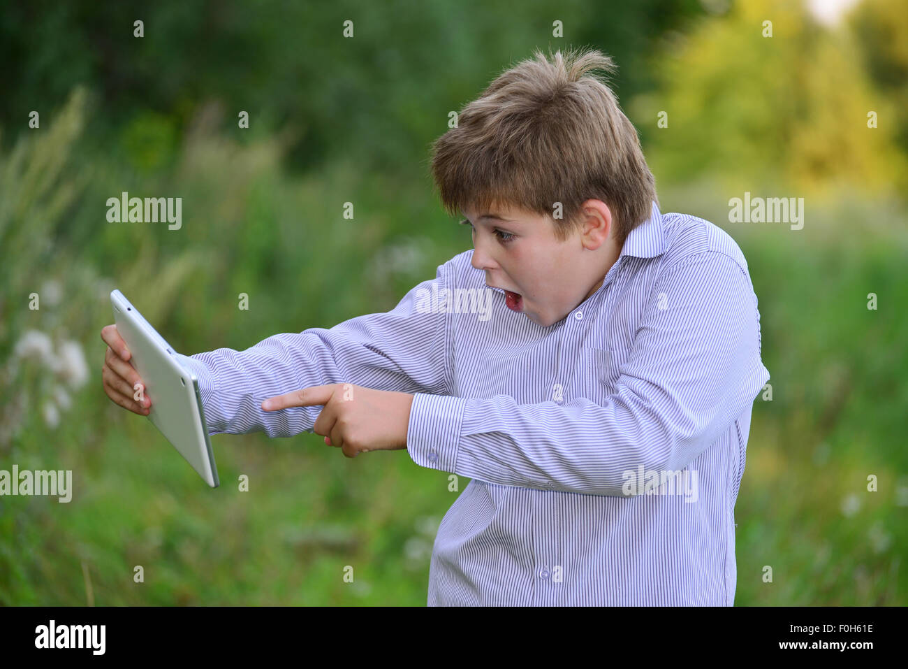 Teen boy con computer tablet in natura Foto Stock
