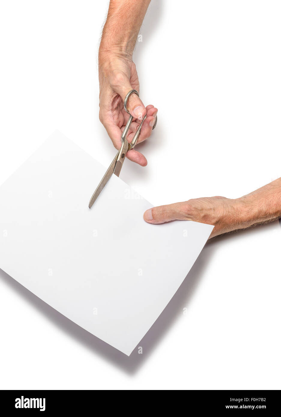 Un uomo è il taglio di un foglio di carta bianca utilizzando forbici metallico, su sfondo bianco Foto Stock
