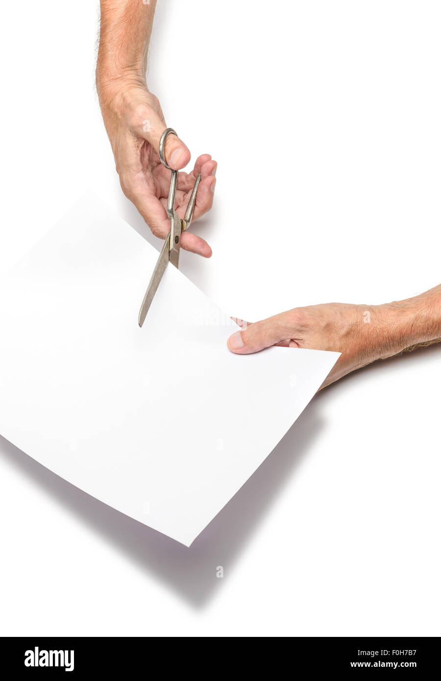 Un uomo è il taglio di un foglio di carta bianca utilizzando forbici metallico, su sfondo bianco Foto Stock