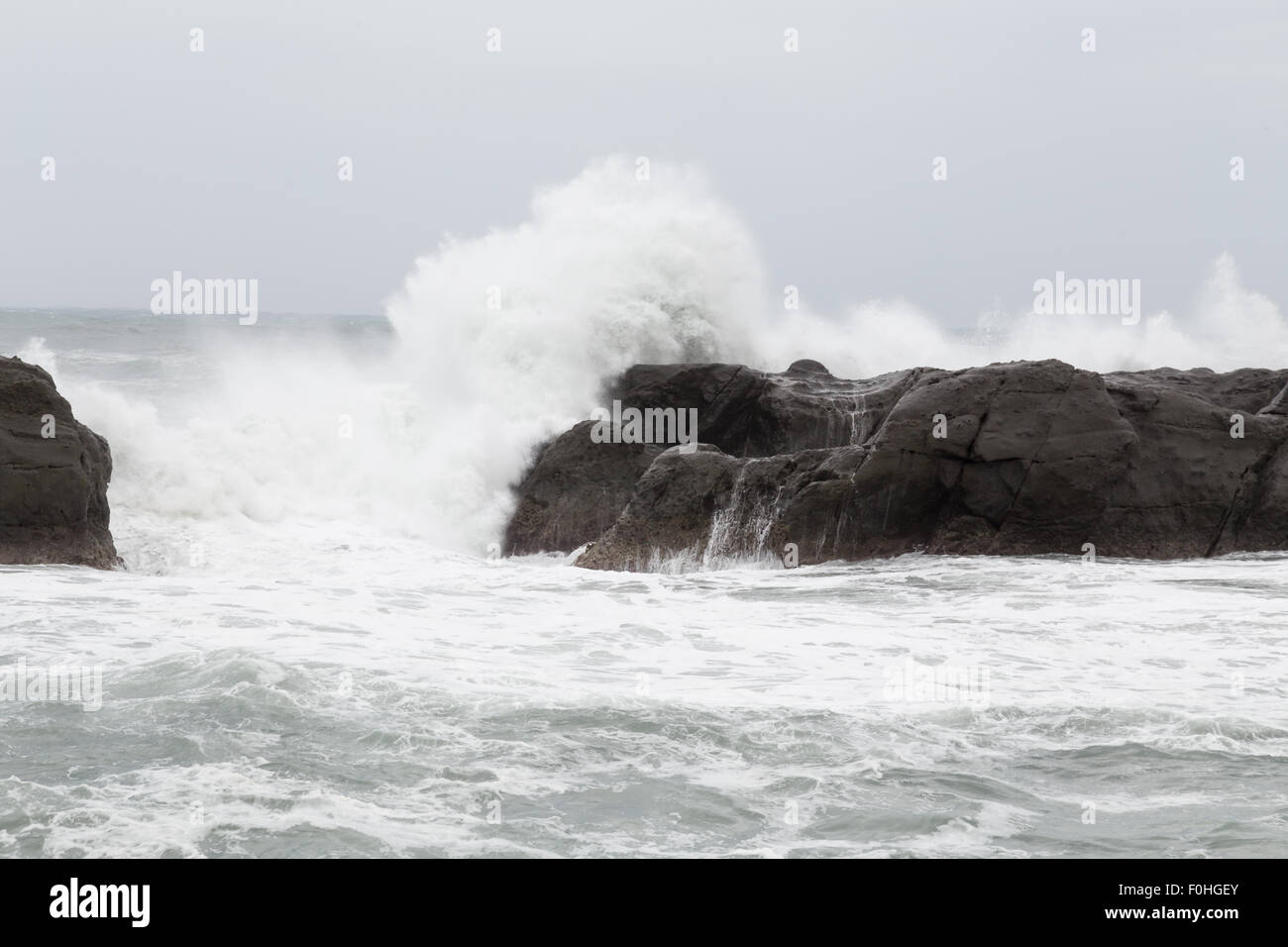 Mare tempestoso con le onde che si infrangono sulle rocce durante il tifone Souledor Foto Stock