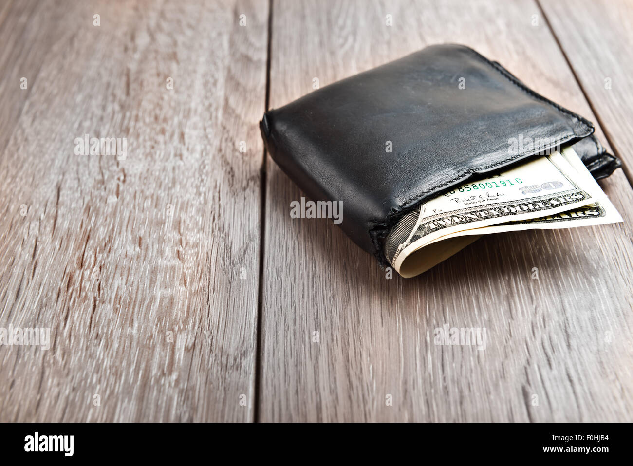 Portafoglio con centinaia di dollari di banconote, su sfondo di legno Foto Stock