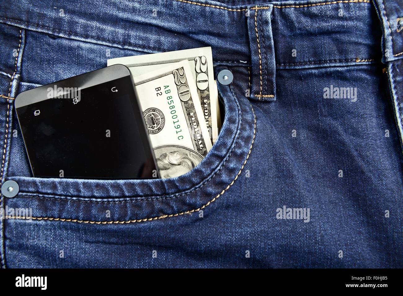 Il denaro e lo smartphone nella tasca dei jeans Foto Stock