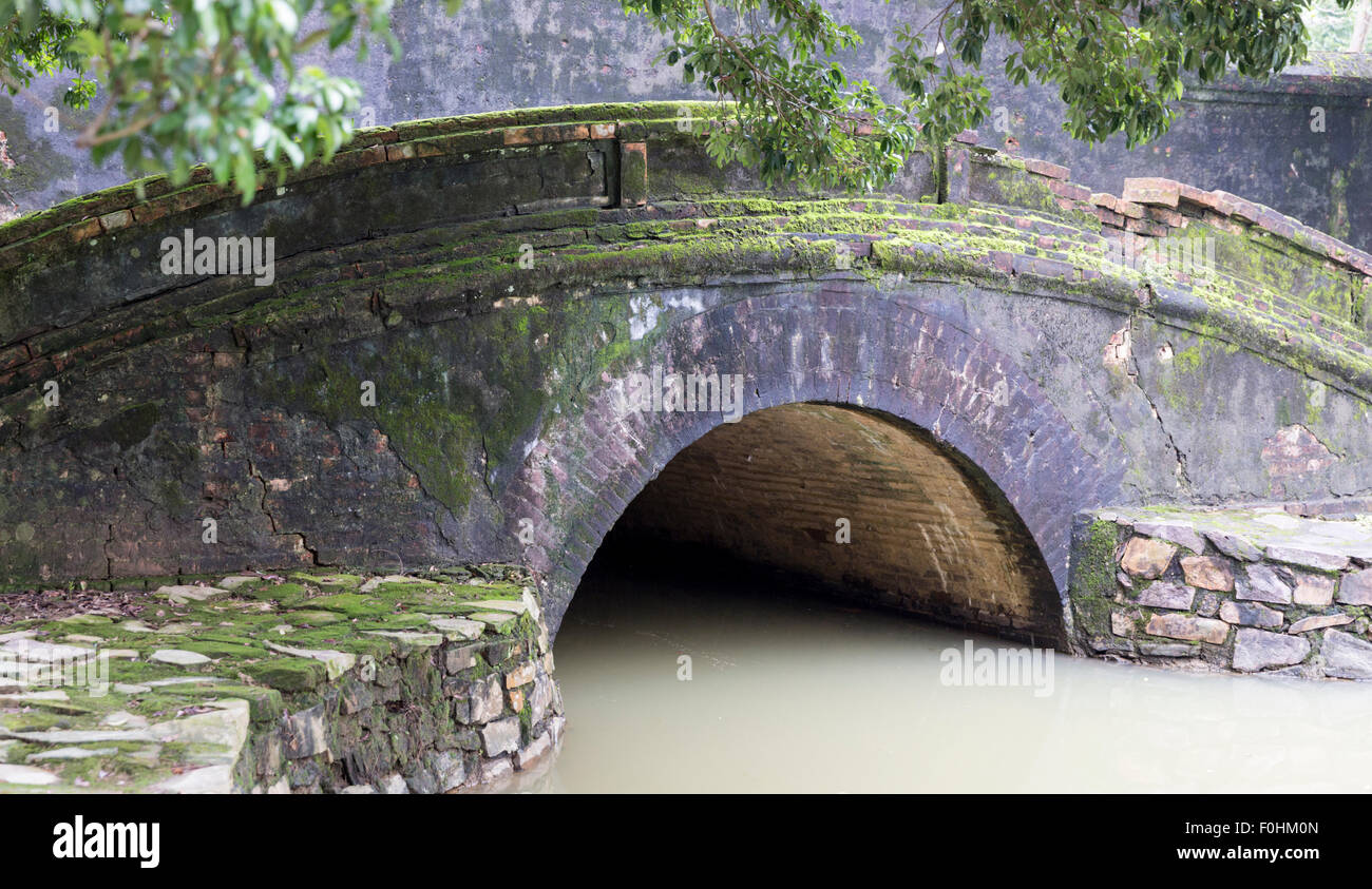 Moss coperto il ponte di pietra presso la tomba della dinastia Nguyen Imperatore Min Mang nel villaggio di un bang vicino a tonalità, Vietnam Foto Stock