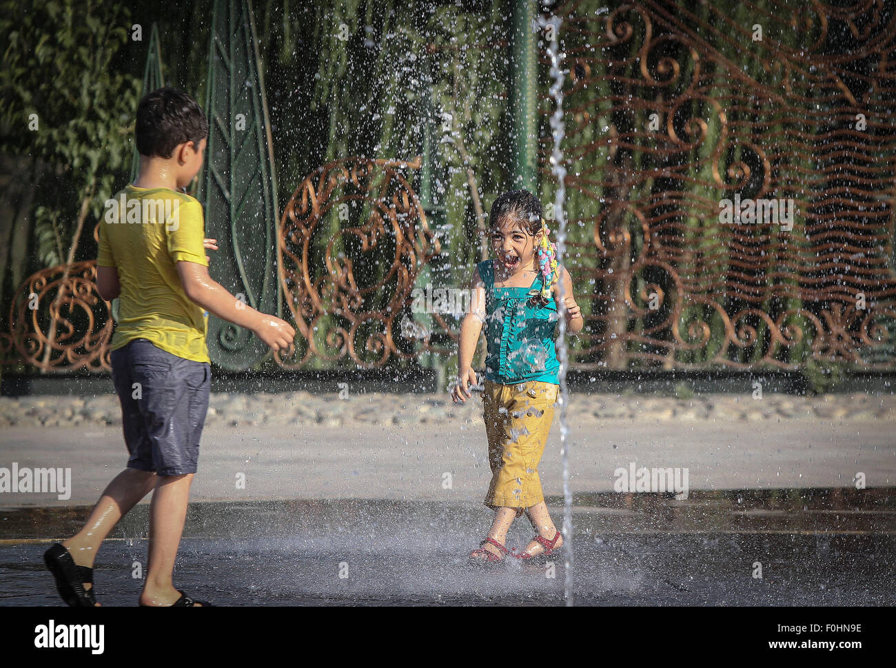 Tehran, Iran. 16 Ago, 2015. Iraniane di giocare i bambini con acqua in un parco in Tehran, Iran, su agosto 16, 2015. Una ondata di caldo con temperatura di oltre 38 gradi Celsius spazzare la città. Credito: Ahmad Halabisaz/Xinhua/Alamy Live News Foto Stock