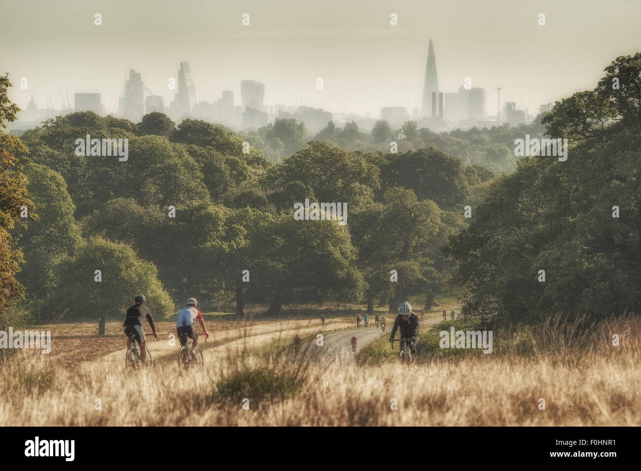 I ciclisti a cavallo attraverso il parco di Richmond con lo skyline di Londra in distanza Foto Stock