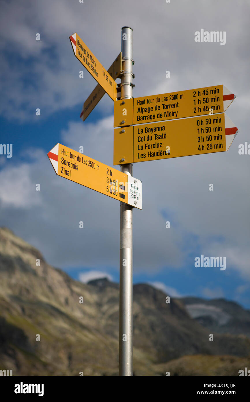 Cartello stradale nelle montagne del Cantone del Vallese, vari segni con le direzioni e le distanze tra i famosi punti di riferimento Foto Stock