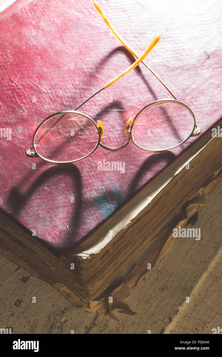 Vecchio vintage occhiali rotondi e vecchio libro. Luce bassa Foto Stock